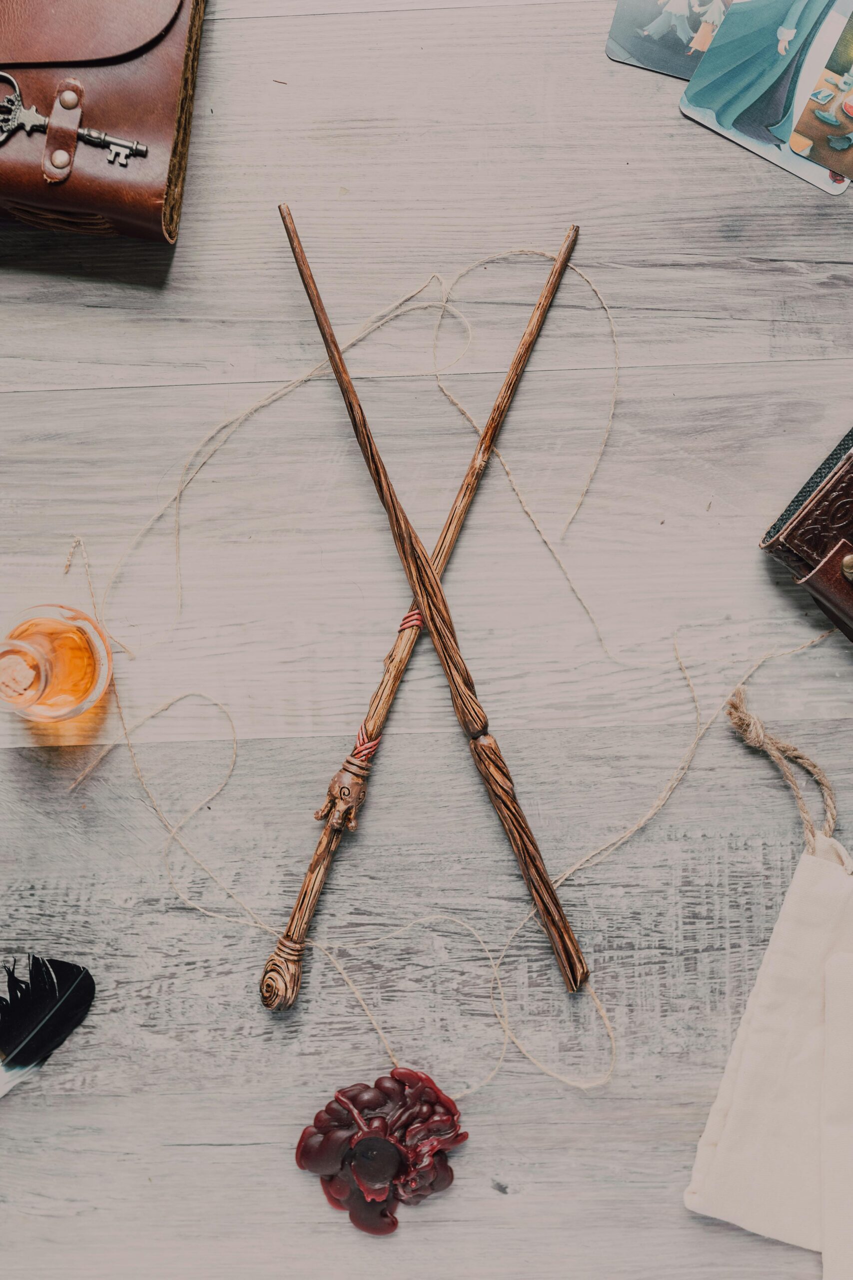 Two wooden wands crossed on a rustic table with wizarding items.